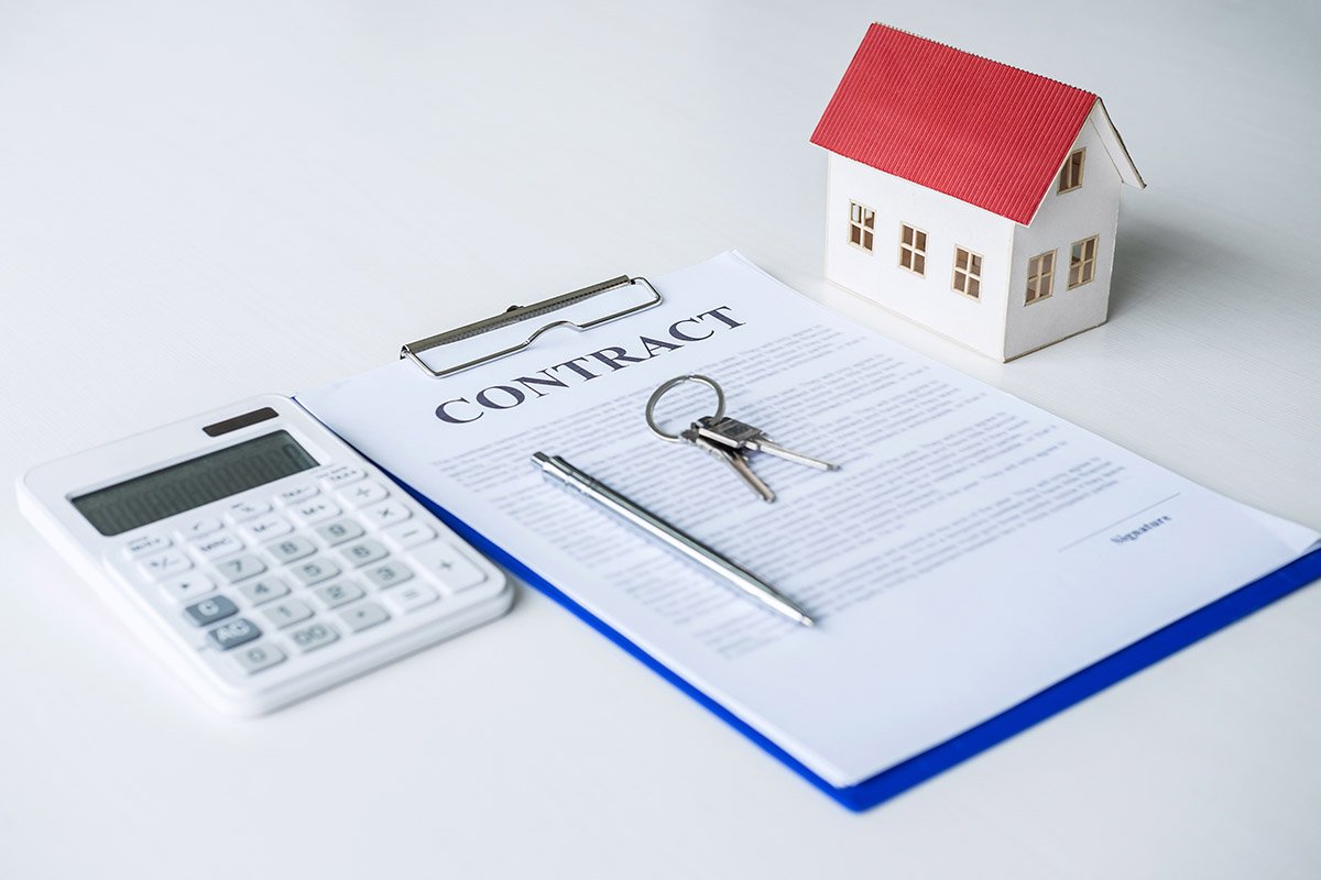 House model, calculator and house key lying on real estate contract, home loan and investment concept.
